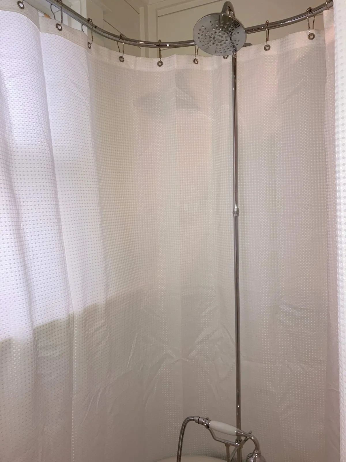 This image focuses on a calming bathroom scene, highlighting a shower head and curtain. The mood is relaxing, suggesting a refreshing spot to unwind or clean off after a day spent in town or at the beach.